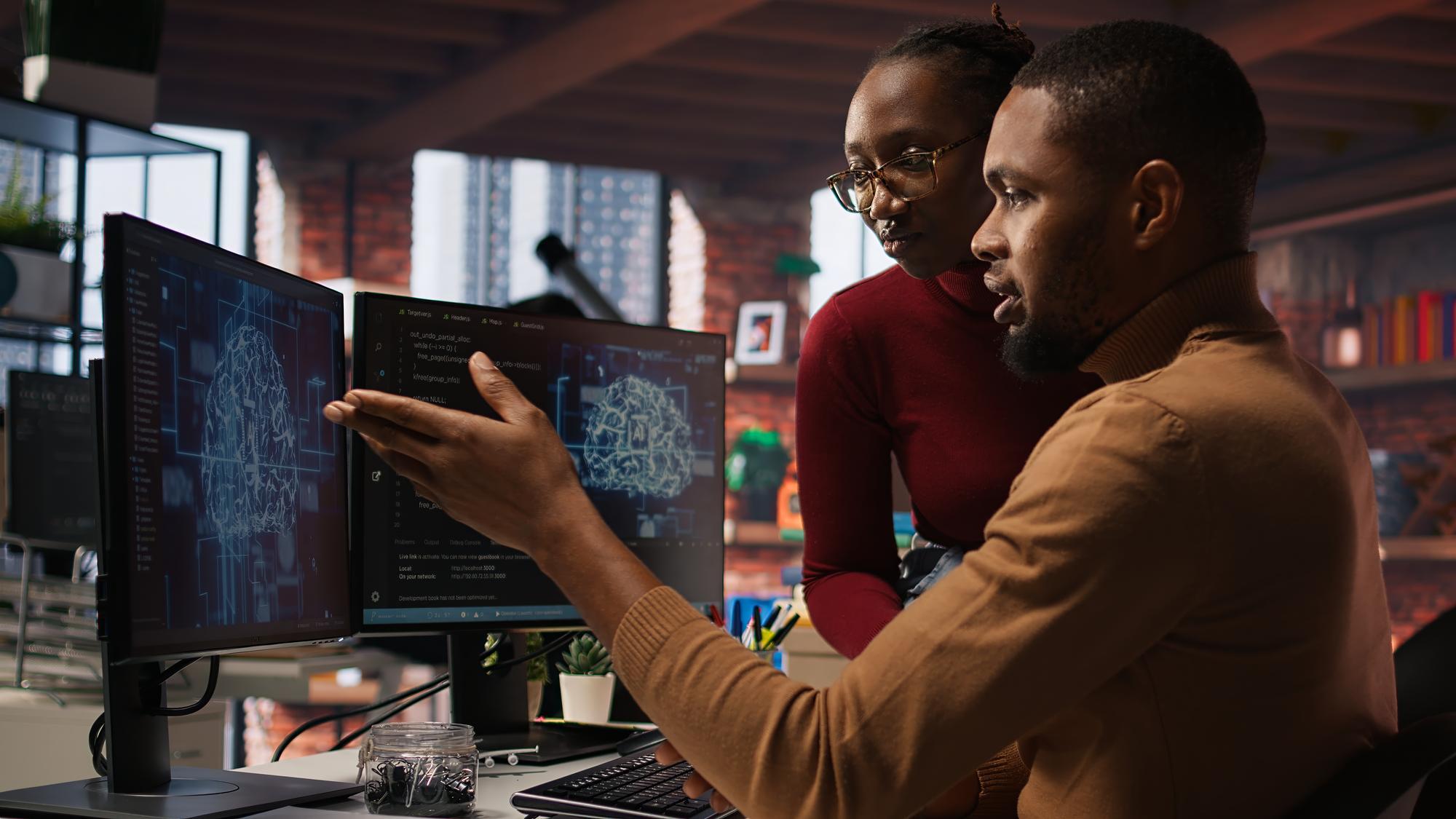 Colleagues discussing a project at a workstation
